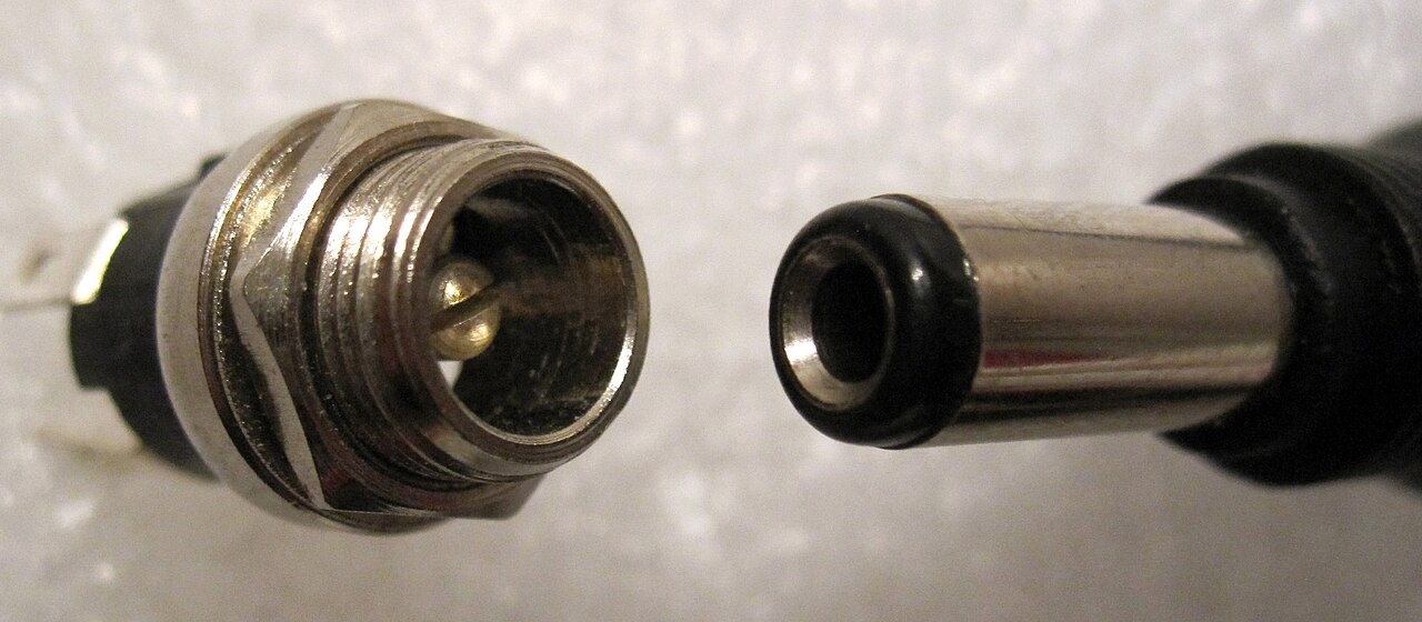 A panel-mount barrel jack facing a 5.5 by 2.5 millimeter barrel plug, center pin visible