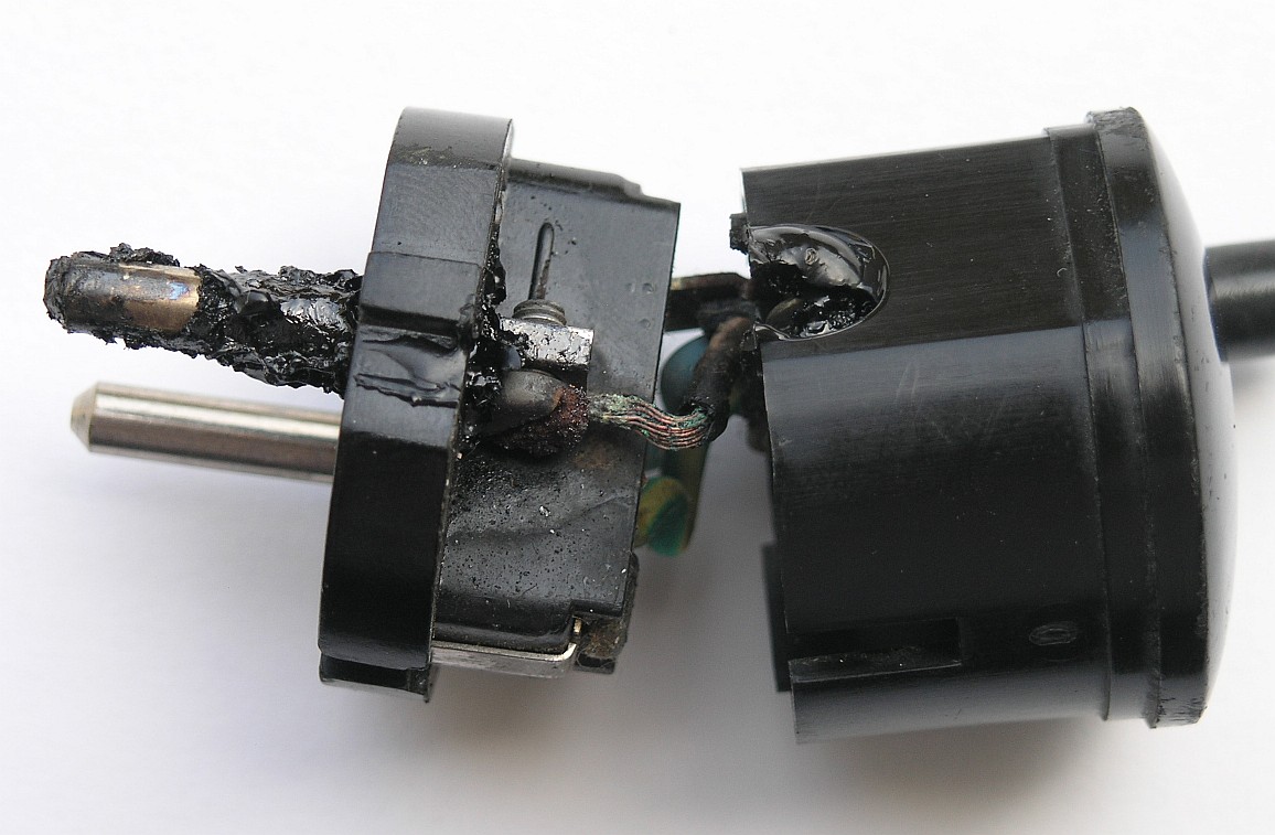 Opened mains plug with heat-damaged terminals and tinned stranded conductors at the screw connections