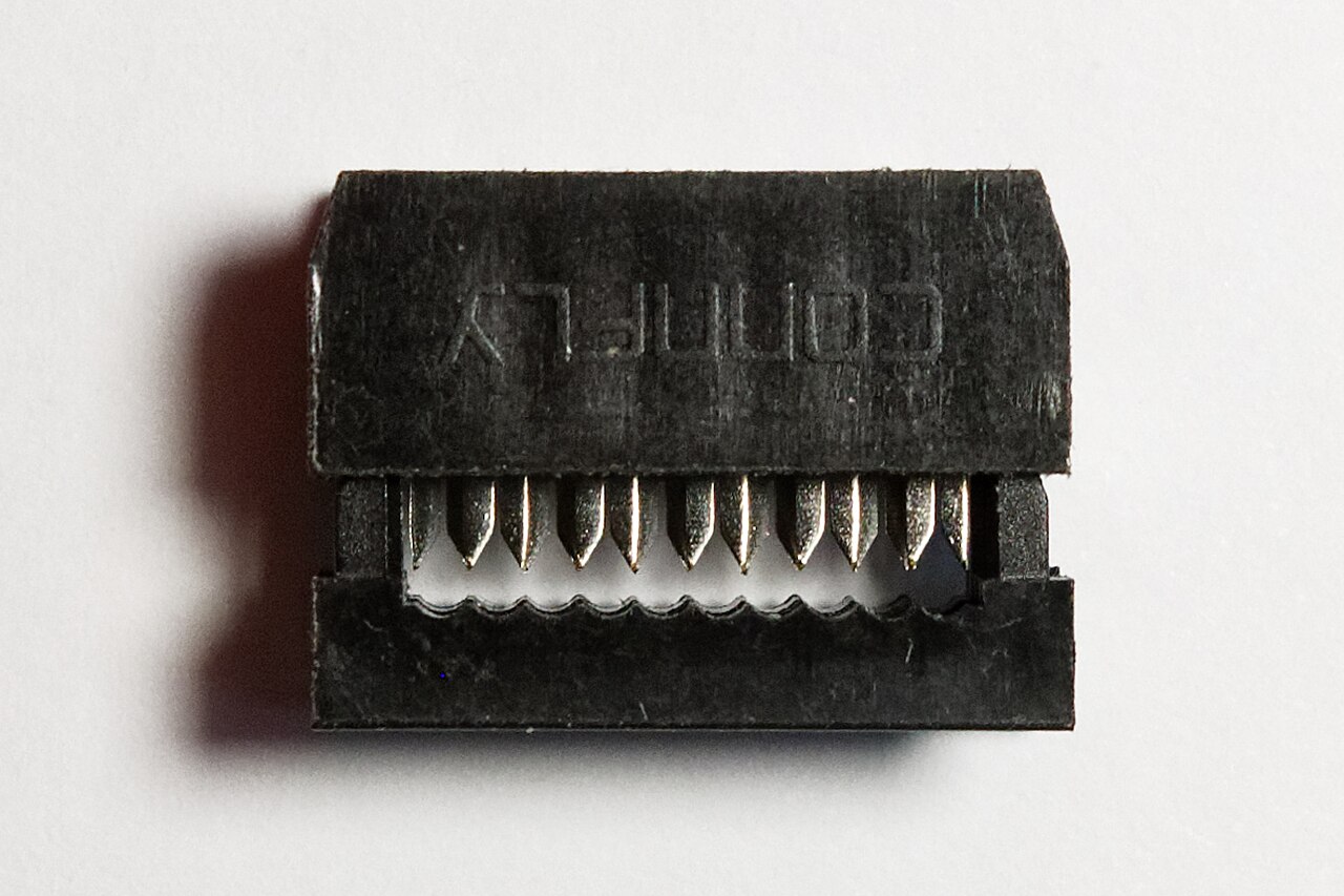 An open 10-position IDC ribbon connector showing the rows of insulation-displacement blade contacts