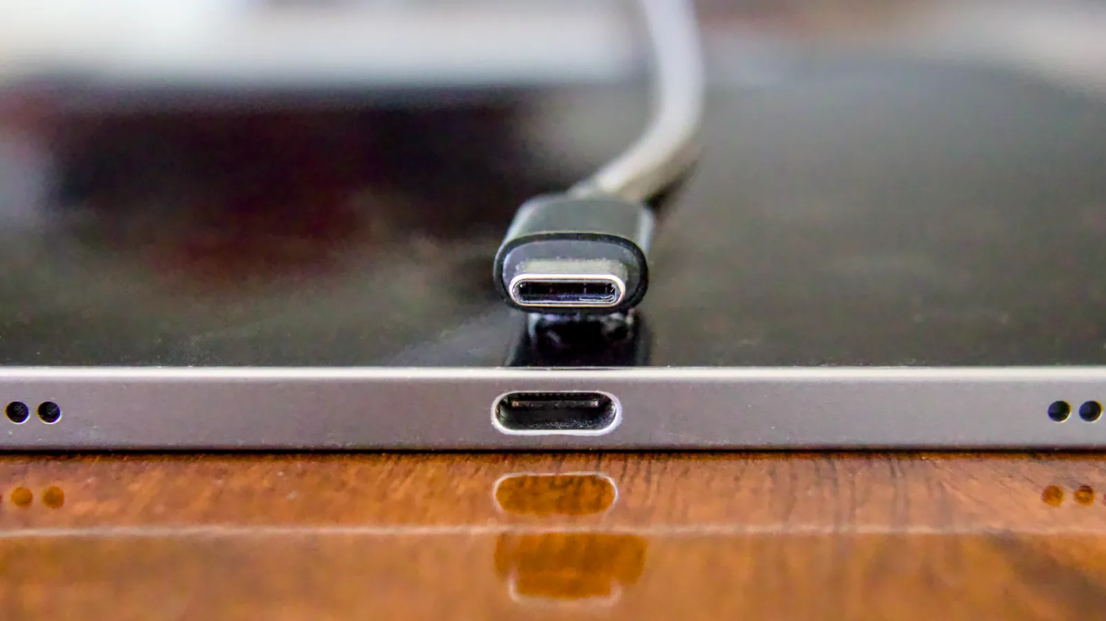 A USB-C cable plug aligned above a USB-C receptacle in the edge of a tablet
