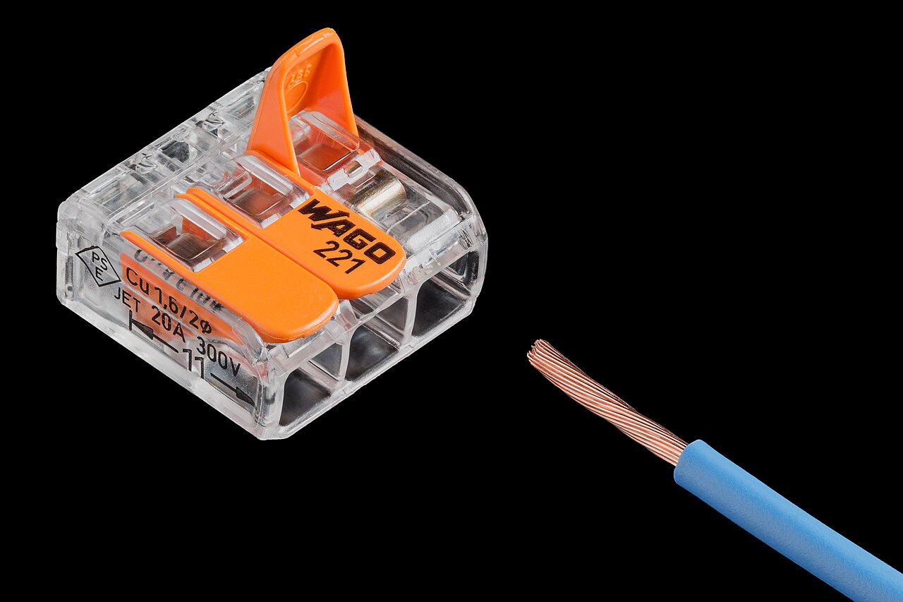 A transparent WAGO 221 lever connector next to a stripped stranded wire