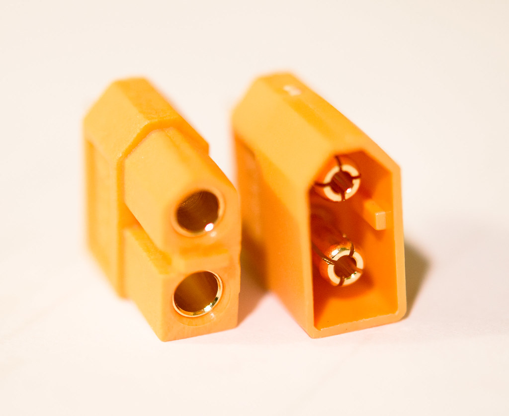 The mating ends of a yellow XT60 pair, showing the keyed shell and two bullet contacts