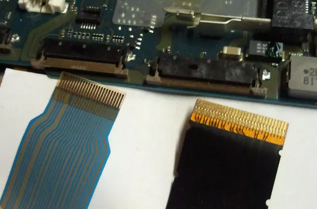 Two flat-flex cables with exposed contacts in front of matching ZIF board connectors